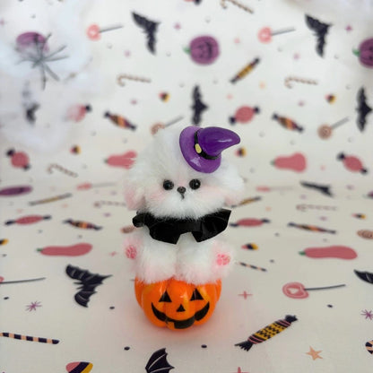 White fluffy friend on a pumpkin with a purple witch hat and black bow.