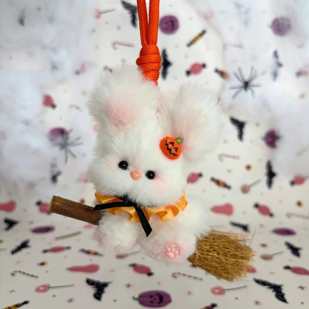 White long-eared friend on a broom with a pumpkin charm and orange ruff.