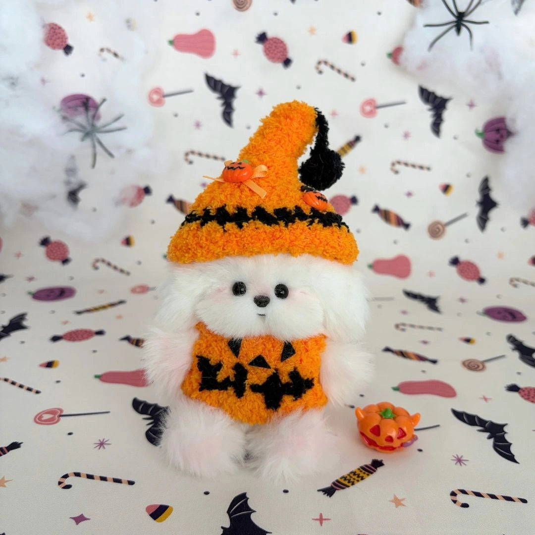 White fluffy friend in an oversized orange witch hat and pumpkin outfit.