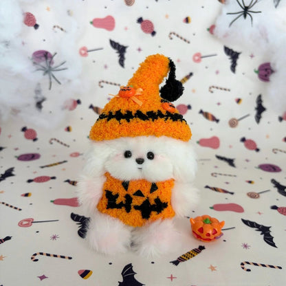 White fluffy friend in an oversized orange witch hat and pumpkin outfit.