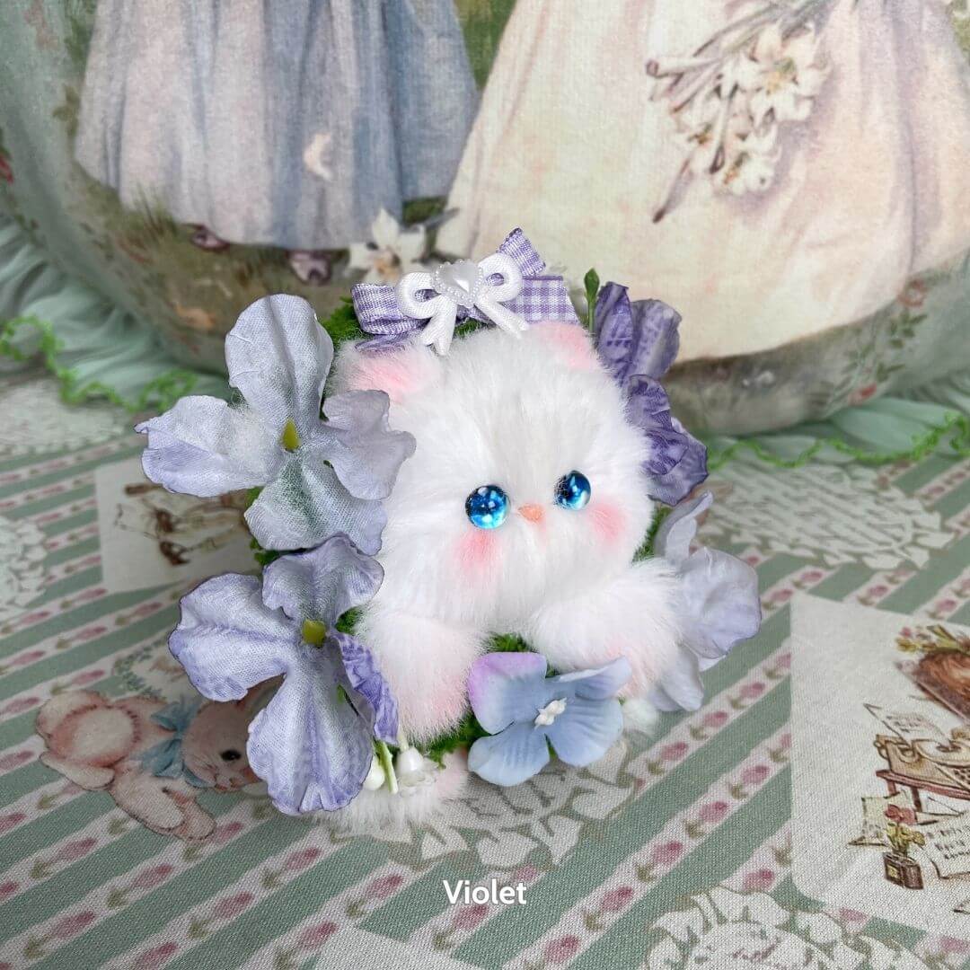 Handmade kitten from the Blossom Kitten Collection, fluffy white with blue accents, surrounded by purple flowers and a bow, kawaii style.