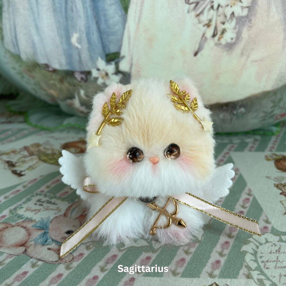 Sagittarius Zodiac Kitten plush with gold leaf accessories, wings, and bow, part of handmade Zodiac Kitten Collection.